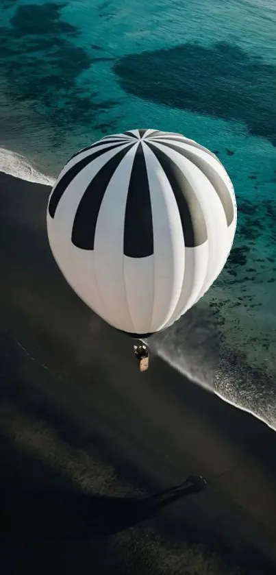 Hot air balloon floats over a teal ocean shore.