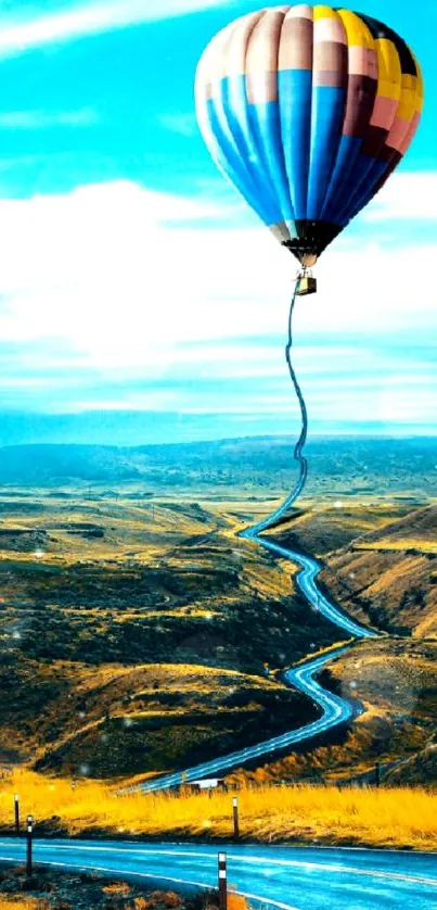 Hot air balloon over winding road in scenic landscape.