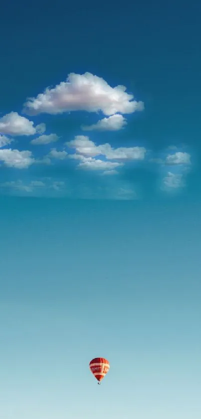 Hot air balloon under a clear blue sky with clouds.