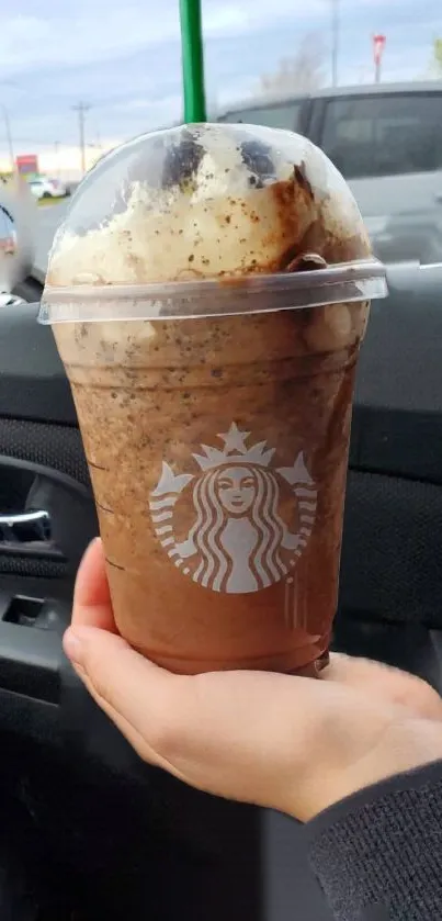 Iced coffee in a car setting with hand holding the cup.