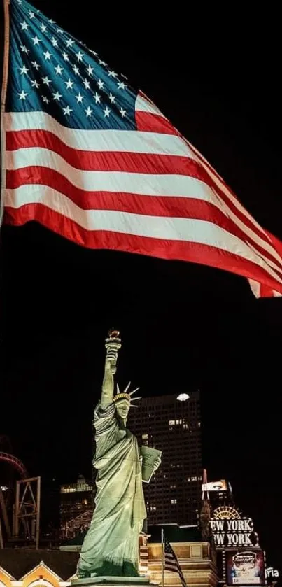 Statue of Liberty at night with American flag waving in dark urban backdrop.