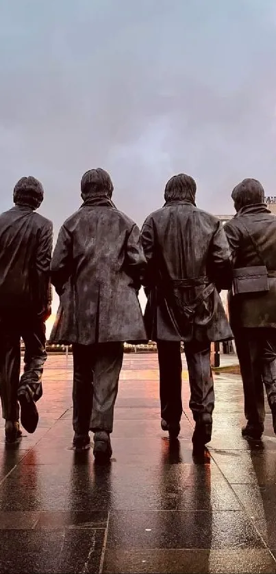 Four iconic statues walking in an urban city setting at dusk with reflections on wet pavement.