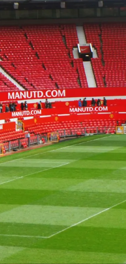 A vibrant football stadium with red seats and a green field, perfect for sports fans.