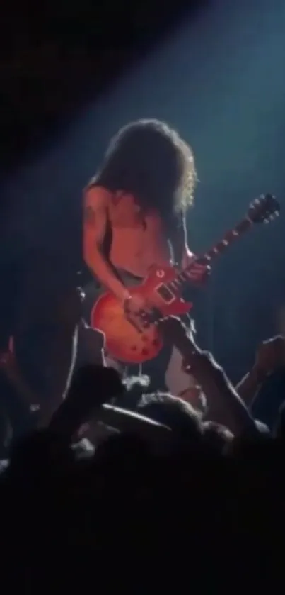 Guitarist performing live on stage with a vibrant concert crowd.