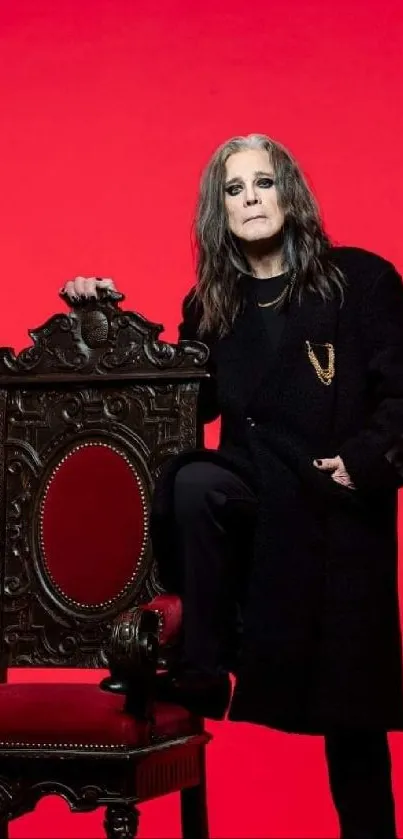 Rock star poses with vintage chair against red background.