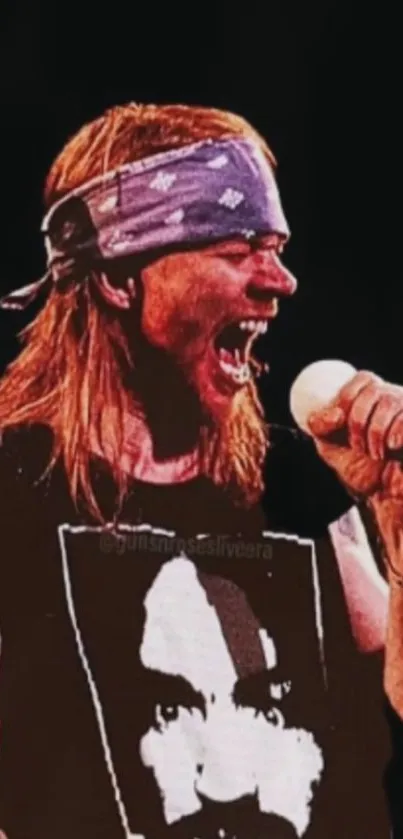 Rock star singing passionately on stage with mic and bandana.