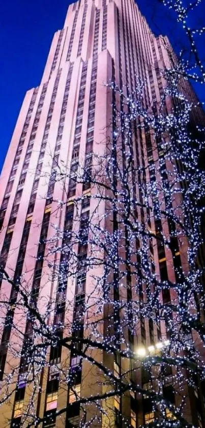 A towering skyscraper illuminated at night with vibrant blue sky.