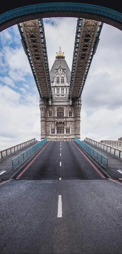 Tower Bridge seen through arch with road leading to it under cloudy skies.