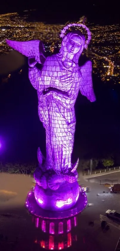 Illuminated purple angel statue at night overlooking a cityscape.