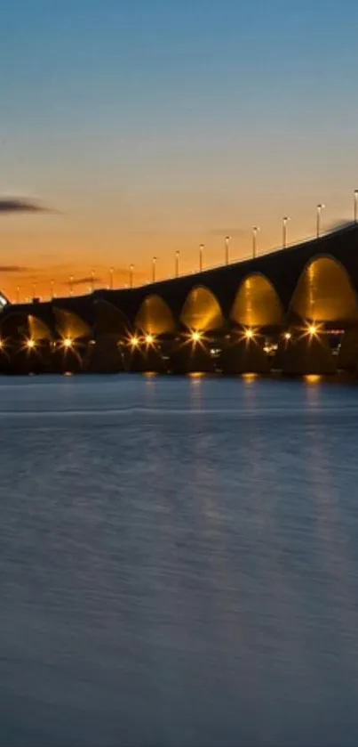 Illuminated bridge over water at sunset.
