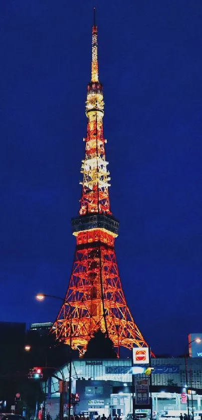 Orange-lit tower against dark blue evening sky in urban setting.