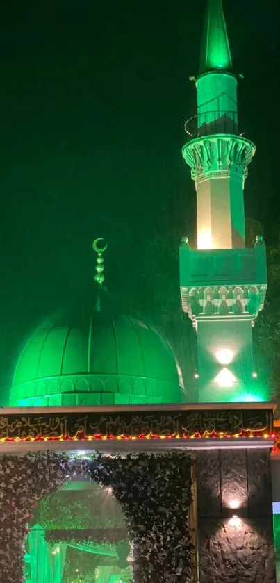 Green illuminated mosque at night with glowing dome and minaret.