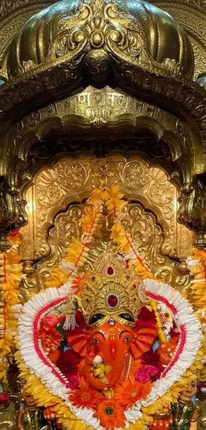 Golden Ganesh idol with floral garlands on ornate background.