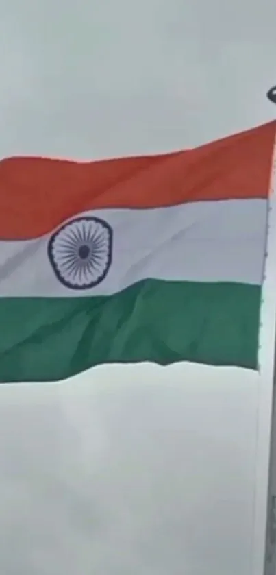 Indian flag waving against a cloudy sky backdrop.