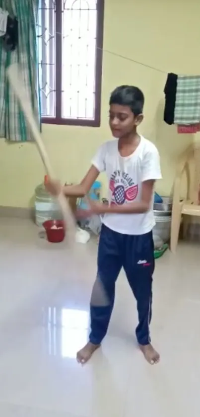 Young boy practicing cricket indoors with bat.