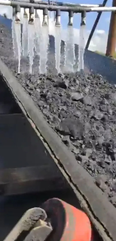 Close-up of coal conveyor with water streams.