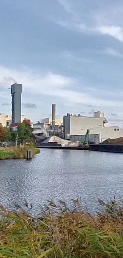 Industrial cityscape by river under blue sky.