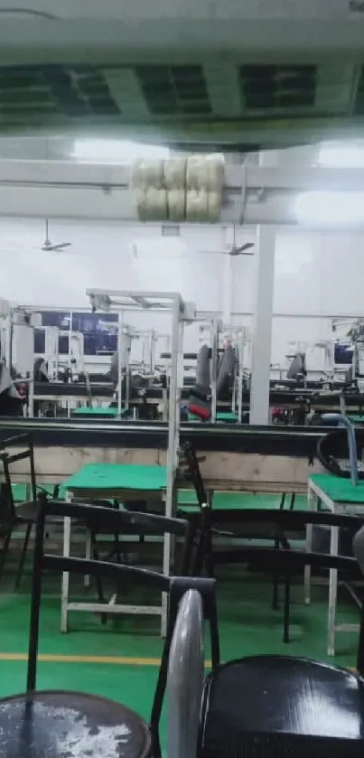 Interior of an industrial sewing facility with equipment and green tables.