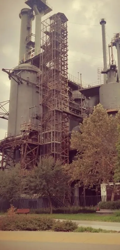 Old industrial structure and trees under a grey sky wallpaper.