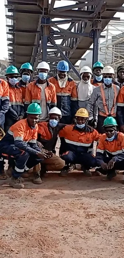 Industrial workers in orange uniforms and helmets at a construction site.