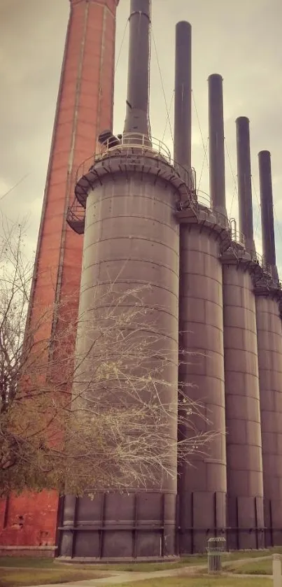 Industrial tower with chimneys against a cloudy sky.