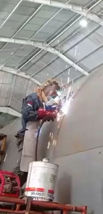 Industrial worker welding indoors with sparks flying.