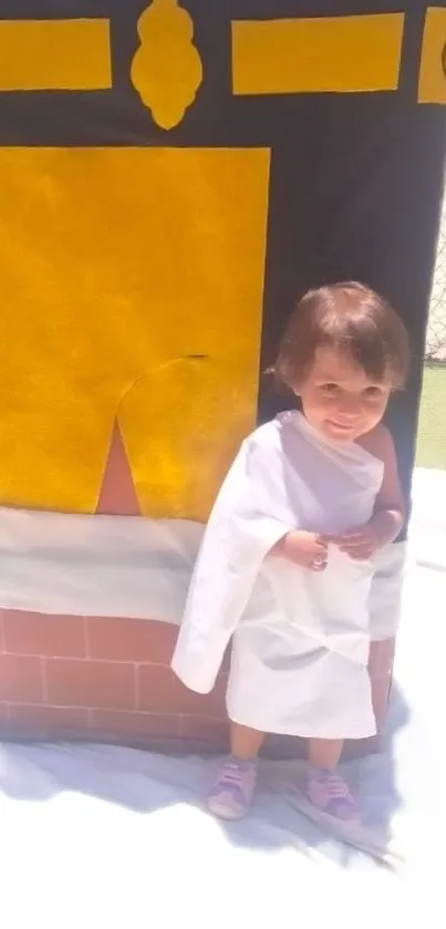 Child in white robe by Kaaba replica.