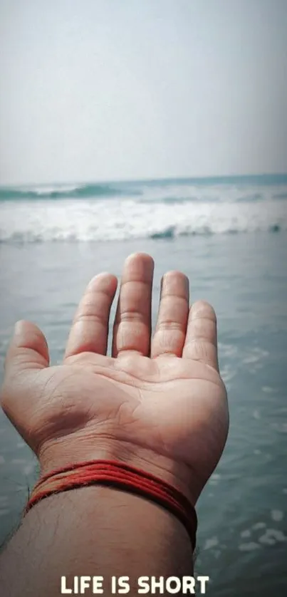 Hand reaching out on a beach with motivational quote.