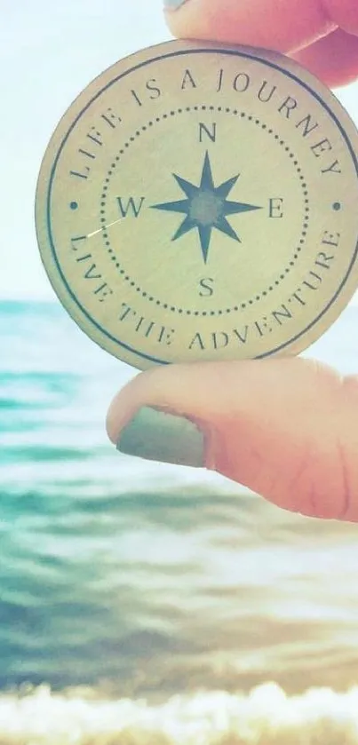 Hand holding a compass with ocean background and inspiring words.