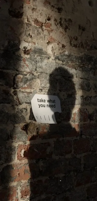 Shadow on a brick wall with 'take what you need' note for an inspiring mobile wallpaper.