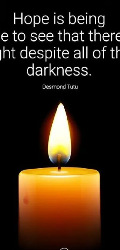 Candle with motivational quote by Desmond Tutu on black background.