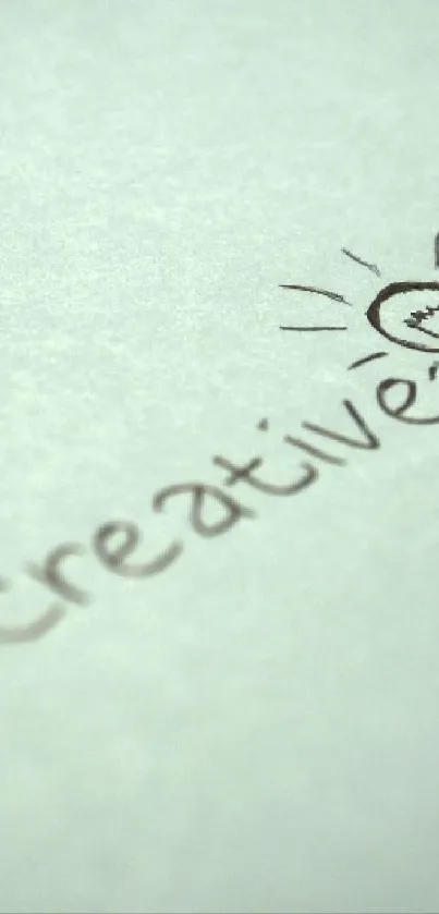 Handwriting "Be Creative" with light bulb drawing on paper.