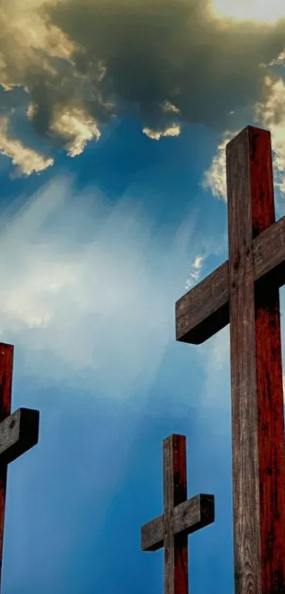 Wooden crosses silhouetted against a blue sky and clouds.