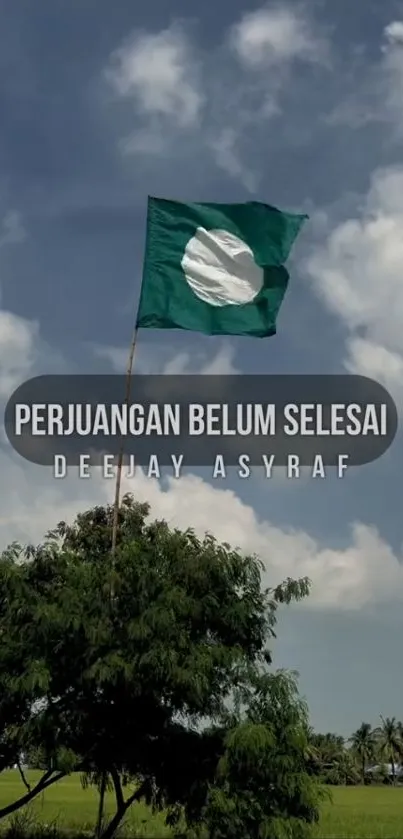 Flag waving under a bright blue sky with lush green landscape.