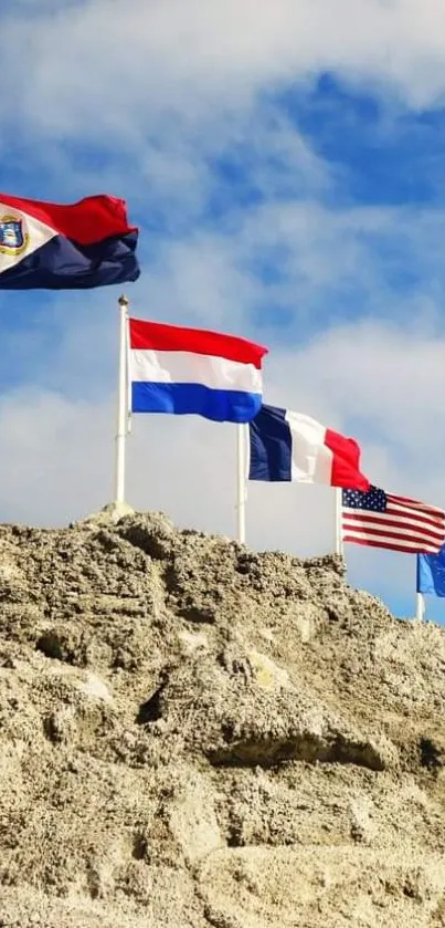 Flags waving on cliff under a bright blue sky.