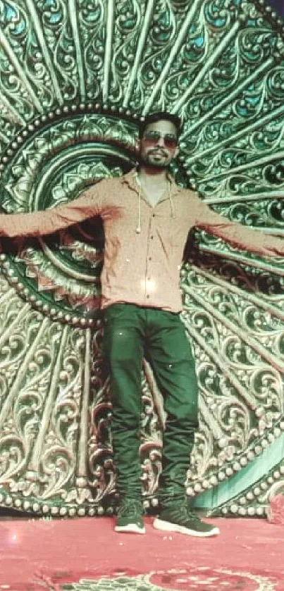 Man posing in front of intricate circular wall art with floral accents.