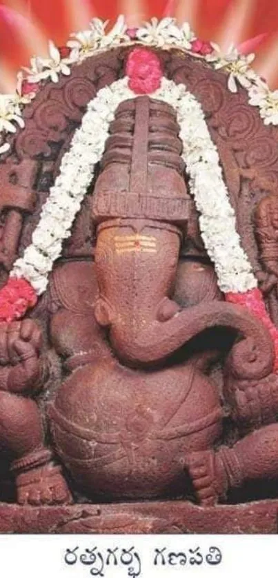 Intricate Ganesh stone sculpture with floral garlands and vibrant red background.