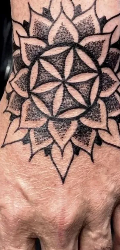 Intricate black ink tattoo design with geometric patterns on a hand.