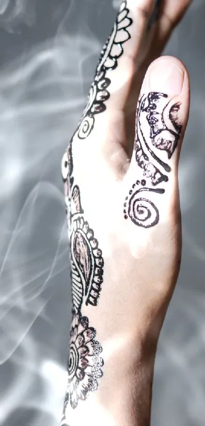 Close-up of a hand with intricate henna and soft smoky background.