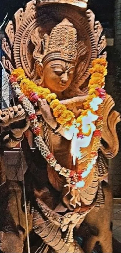 Intricate Hindu statue with orange garlands and a serene background.