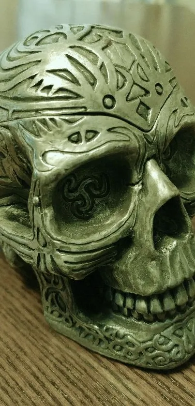 Intricately carved metallic skull artwork on wooden surface.