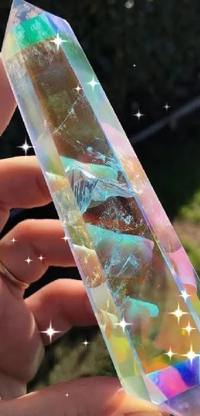 Hand holding an iridescent crystal prism reflecting colorful light.