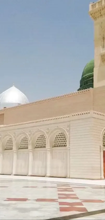 Elegant mosque with domes and arches under a blue sky.