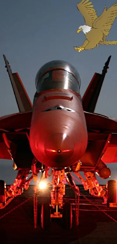 Jet fighter on carrier at night, illuminated by red lights, with eagle above.