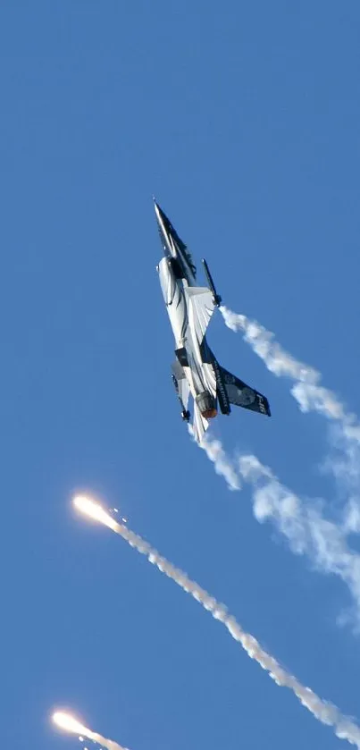 Dynamic jet fighter soaring in blue sky with smoke and flare trails.