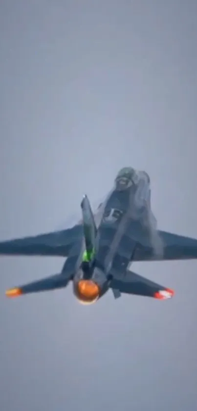 Jet fighter soaring with afterburner flames in clear sky.