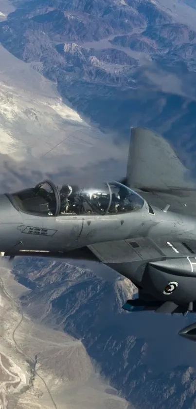 Jet fighter soaring above vast desert mountains.