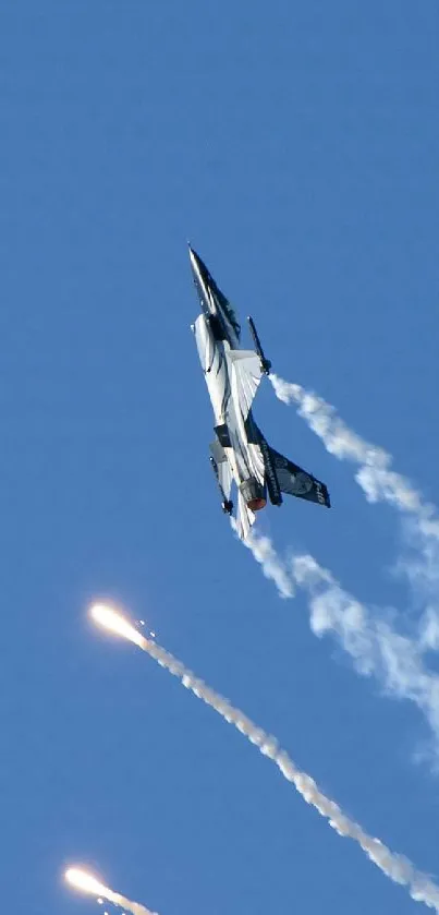 Military jet ascends with trails of smoke in a bright blue sky.