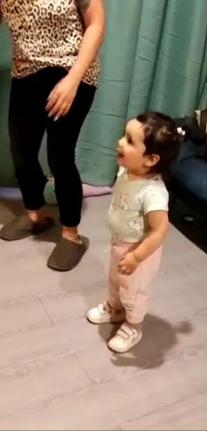 Adorable toddler standing in cozy room with teal curtains.