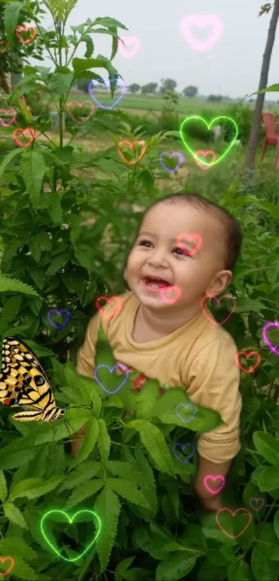 Baby smiling in greenery with hearts and butterfly.